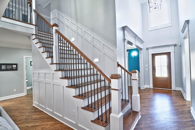 foyer with dark hardwood / wood-style floors, ornate columns, and a towering ceiling