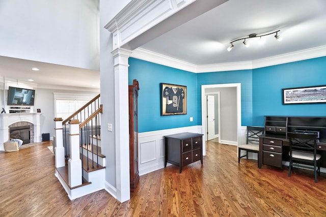 office space featuring decorative columns, rail lighting, dark hardwood / wood-style flooring, and ornamental molding