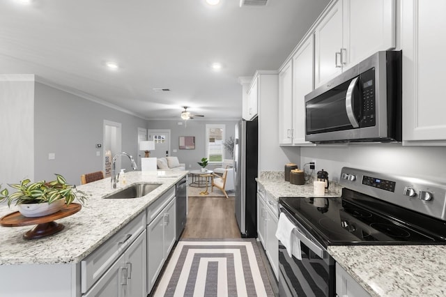 kitchen featuring sink, appliances with stainless steel finishes, ornamental molding, white cabinets, and light stone counters