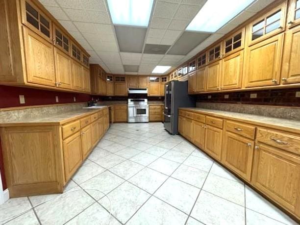 kitchen featuring black refrigerator, a paneled ceiling, stainless steel range oven, and sink