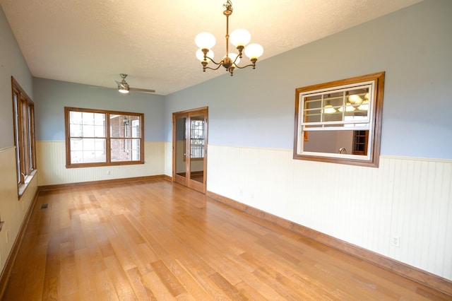 spare room featuring ceiling fan with notable chandelier, a textured ceiling, and light hardwood / wood-style flooring