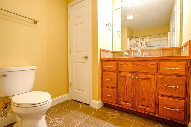 bathroom with toilet, vanity, tile patterned floors, a textured ceiling, and curtained shower