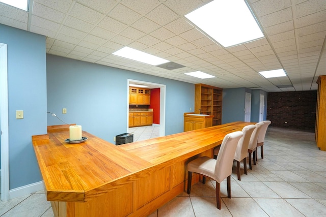 interior space with brick wall and a drop ceiling