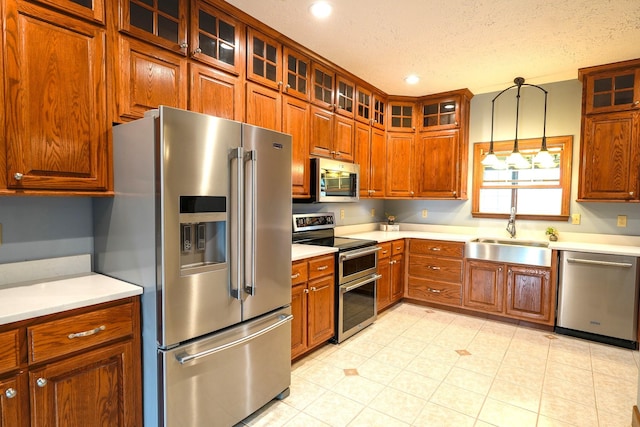 kitchen featuring sink, hanging light fixtures, appliances with stainless steel finishes, and a textured ceiling