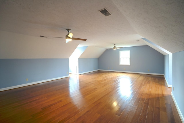 bonus room featuring ceiling fan, wood-type flooring, a textured ceiling, and vaulted ceiling