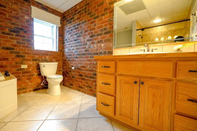 bathroom featuring toilet, vanity, tile patterned floors, and brick wall