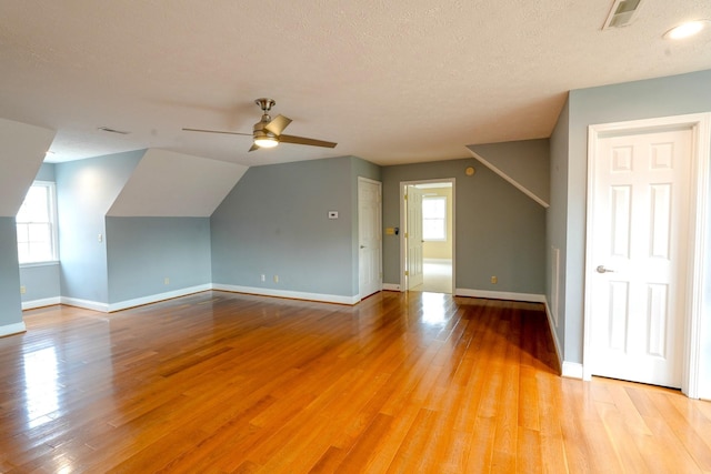 additional living space featuring vaulted ceiling, ceiling fan, a healthy amount of sunlight, and light hardwood / wood-style floors