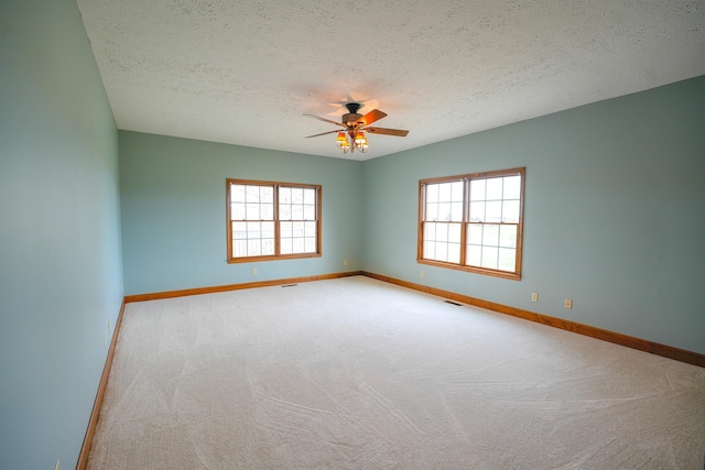 spare room with a textured ceiling, ceiling fan, and light colored carpet