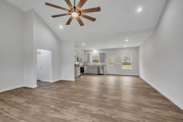 unfurnished living room with ceiling fan, high vaulted ceiling, and hardwood / wood-style floors