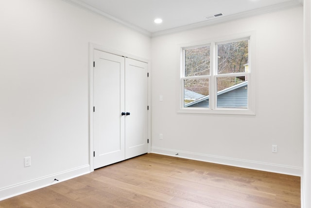 empty room with ornamental molding and light hardwood / wood-style flooring