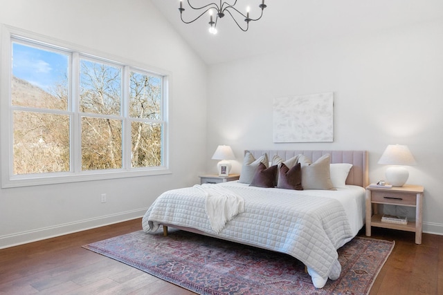 bedroom with vaulted ceiling, baseboards, wood finished floors, and an inviting chandelier