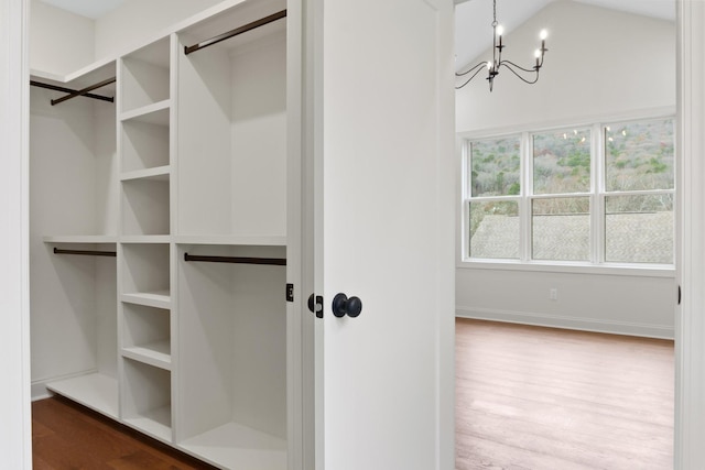 walk in closet with lofted ceiling, a notable chandelier, and wood finished floors