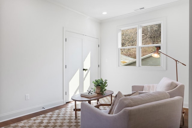 sitting room with ornamental molding, wood finished floors, visible vents, and baseboards