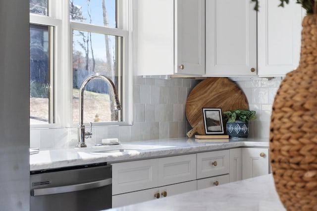 kitchen featuring tasteful backsplash, sink, stainless steel dishwasher, and white cabinets