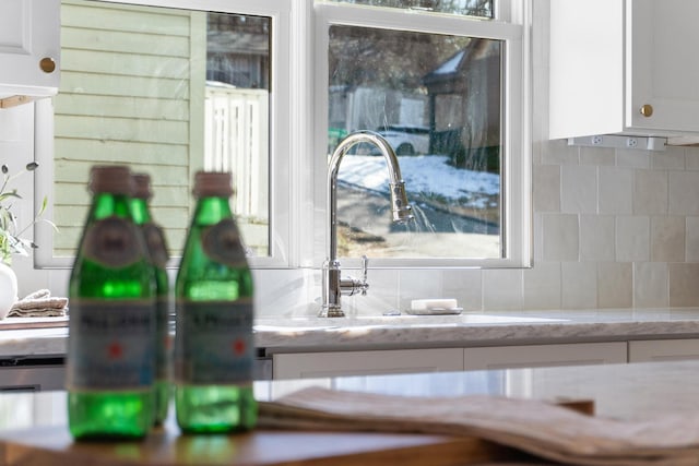 details with white cabinets, light stone counters, decorative backsplash, and a sink