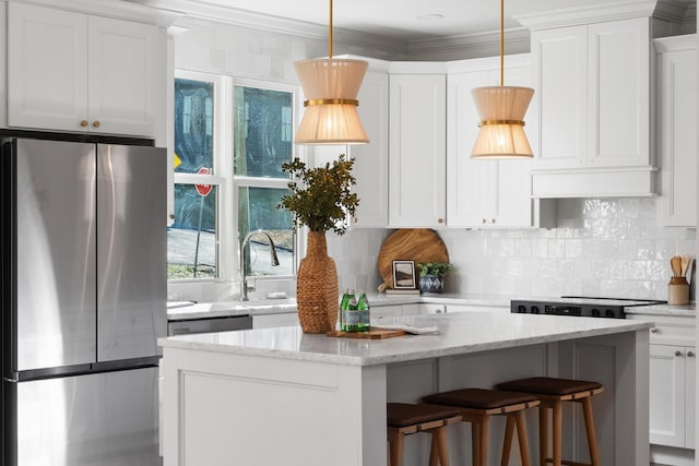 kitchen with crown molding, decorative backsplash, freestanding refrigerator, white cabinetry, and a kitchen island