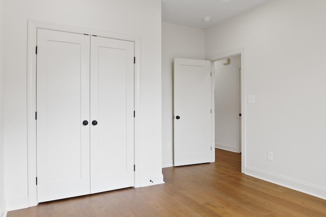 unfurnished bedroom with a closet, baseboards, and wood finished floors