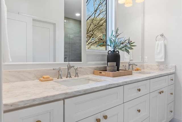 bathroom with double vanity, a shower stall, and a sink