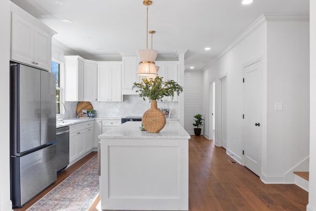 kitchen with stainless steel appliances, white cabinetry, and hanging light fixtures