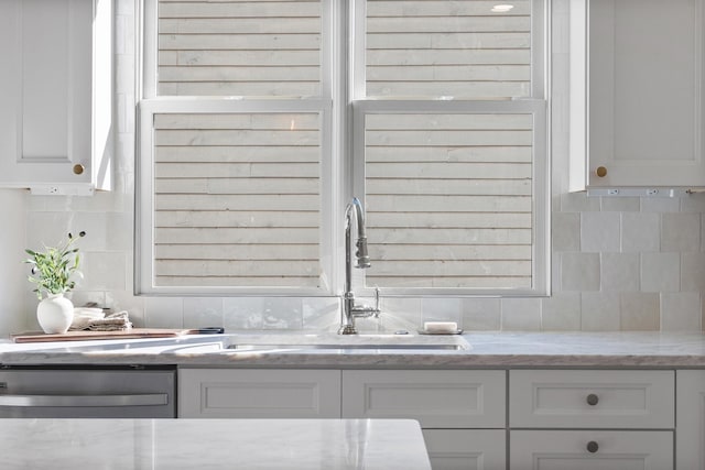 interior space featuring white cabinets, decorative backsplash, and dishwasher