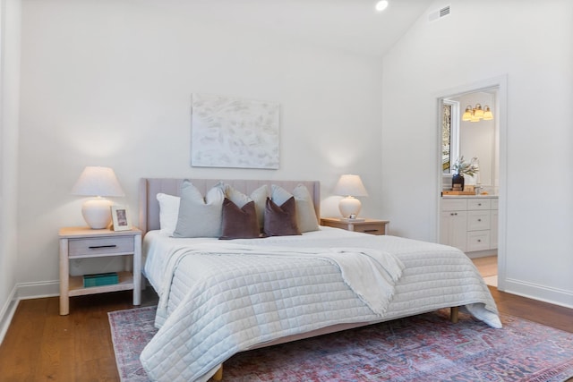 bedroom with connected bathroom, hardwood / wood-style floors, and vaulted ceiling