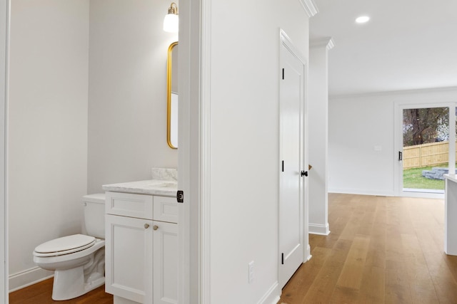 bathroom featuring hardwood / wood-style flooring, vanity, crown molding, and toilet