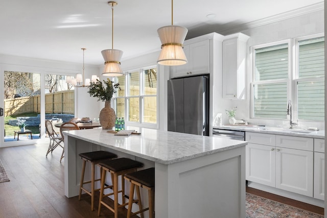 kitchen with light stone counters, a center island, dark wood finished floors, appliances with stainless steel finishes, and a sink