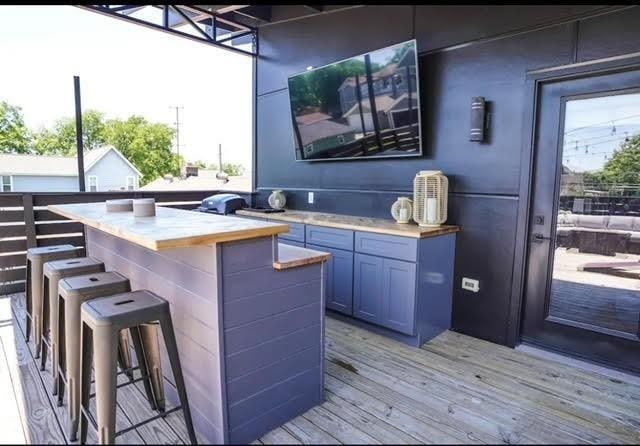 bar featuring light hardwood / wood-style flooring, blue cabinets, and wood counters