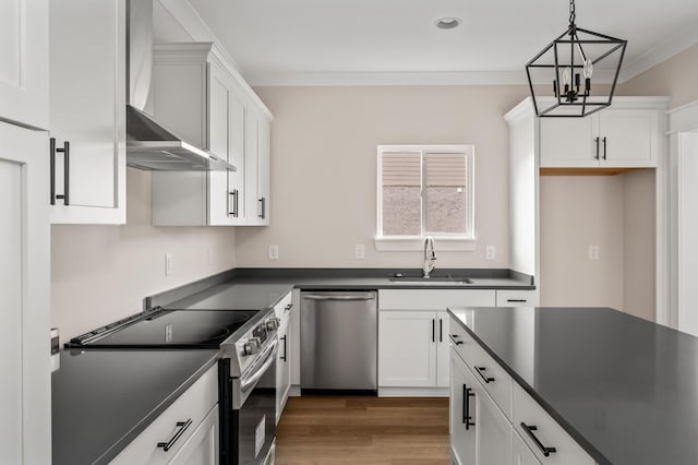 kitchen featuring decorative light fixtures, wall chimney range hood, sink, white cabinetry, and stainless steel appliances