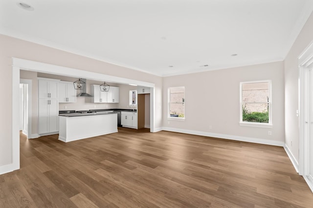 unfurnished living room featuring hardwood / wood-style floors, crown molding, and plenty of natural light