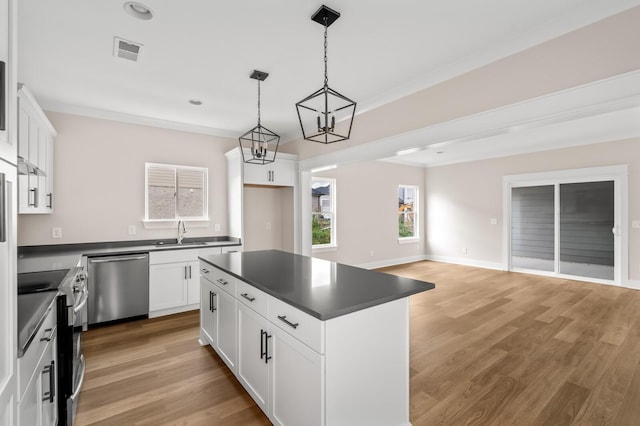 kitchen featuring stainless steel appliances, pendant lighting, white cabinets, and a center island