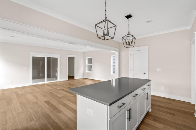 kitchen featuring light wood-type flooring, ornamental molding, white cabinetry, and pendant lighting