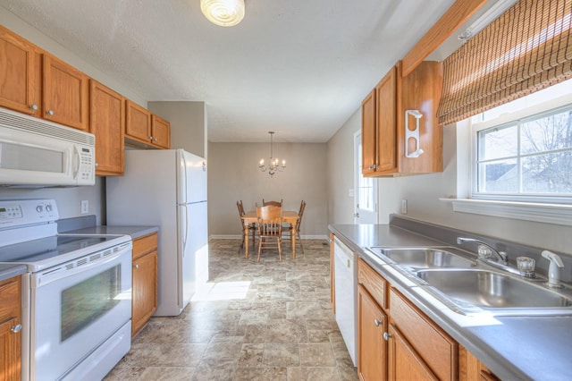 kitchen with a chandelier, sink, hanging light fixtures, and white appliances