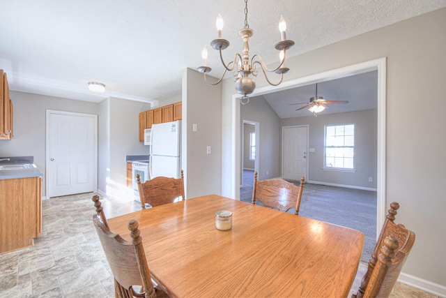 dining area featuring ceiling fan with notable chandelier, sink, a textured ceiling, and lofted ceiling