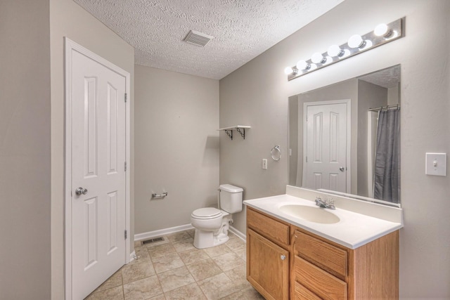 bathroom with a textured ceiling, toilet, and vanity