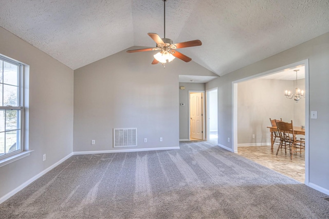 spare room featuring ceiling fan with notable chandelier, a wealth of natural light, a textured ceiling, and lofted ceiling