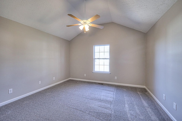 carpeted empty room featuring ceiling fan, vaulted ceiling, and a textured ceiling