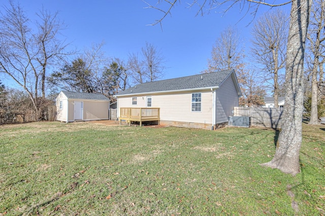 rear view of property featuring a deck, a yard, and a storage shed