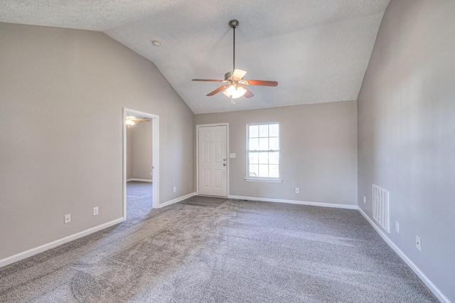 empty room with ceiling fan, vaulted ceiling, a textured ceiling, and carpet flooring