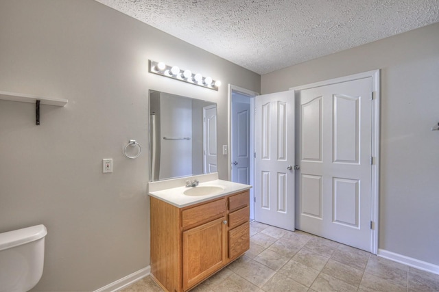 bathroom with toilet, vanity, and a textured ceiling