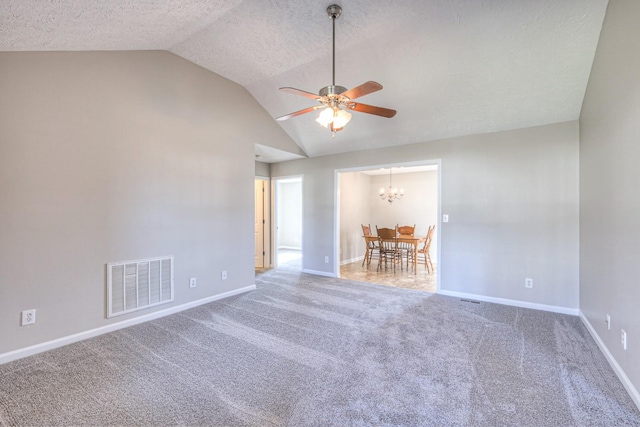 empty room with ceiling fan with notable chandelier, a textured ceiling, lofted ceiling, and carpet flooring