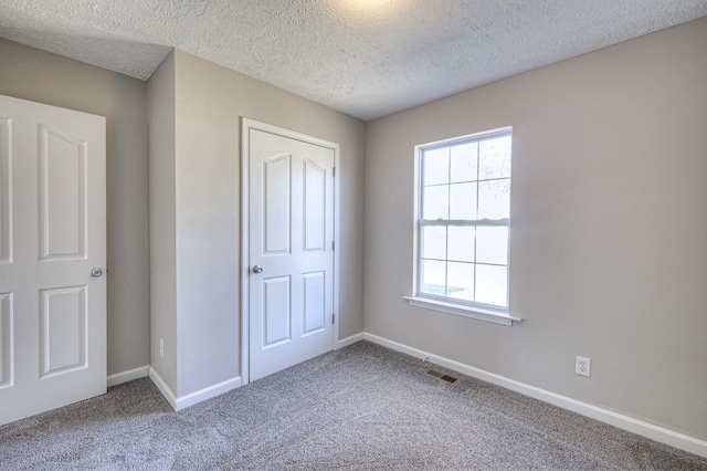 unfurnished bedroom featuring a closet, a textured ceiling, and carpet flooring