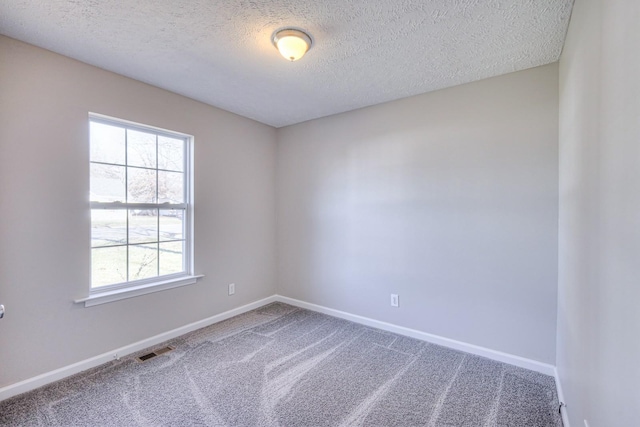 carpeted empty room featuring a textured ceiling