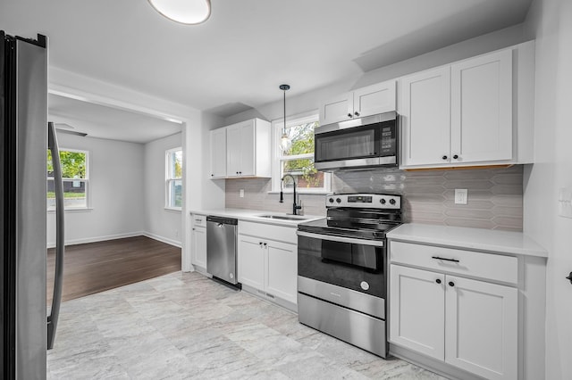 kitchen featuring pendant lighting, sink, white cabinetry, and stainless steel appliances