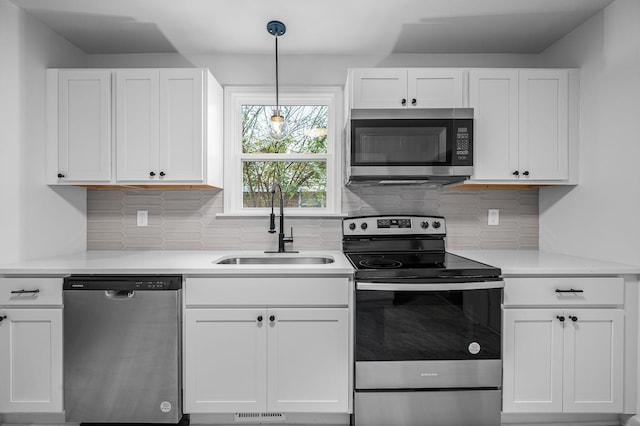 kitchen with decorative light fixtures, sink, white cabinetry, and stainless steel appliances