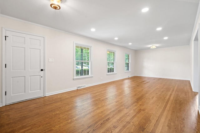 empty room with crown molding and light hardwood / wood-style flooring