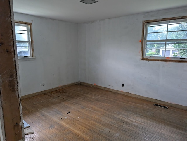 spare room with a wealth of natural light and hardwood / wood-style flooring