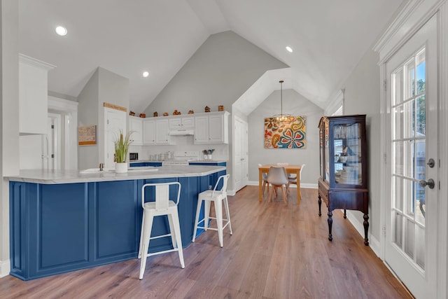 kitchen with kitchen peninsula, an inviting chandelier, white cabinets, and a breakfast bar