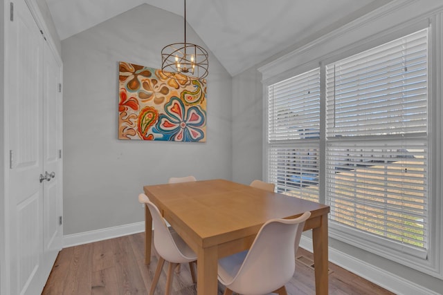 dining area featuring light wood-type flooring, an inviting chandelier, and lofted ceiling