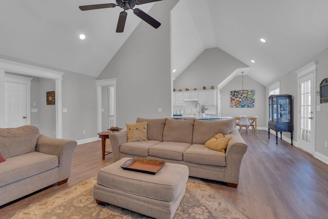 living room with ceiling fan, light wood-type flooring, vaulted ceiling, and sink